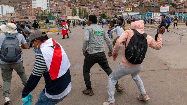 Manifestantes lanzando piedras contra la policía en Cusco.