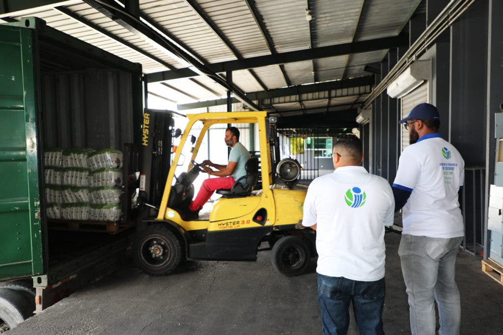 Inspectores de Pro Consumidor observan a empleados de unos de los almacenes intervenidos cargando un camión de azúcar para ser enviados a los detallistas que habían hecho pedido del producto.